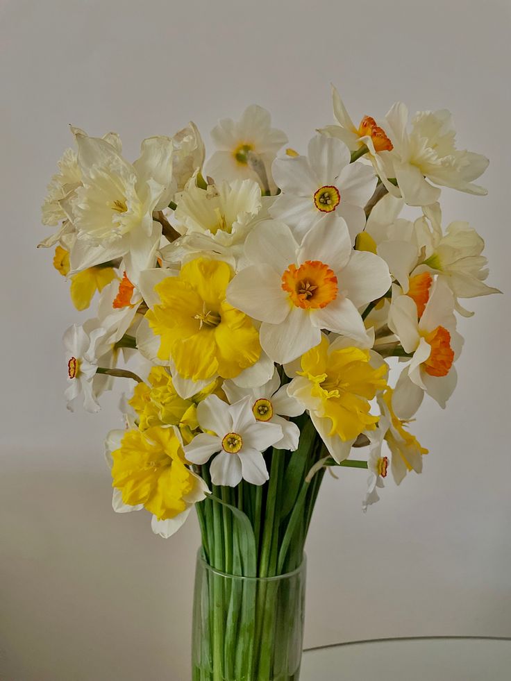 a glass vase filled with yellow and white flowers