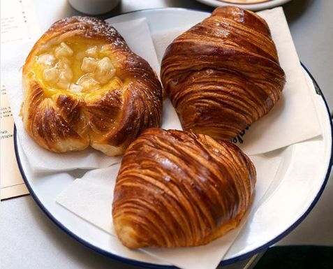 three croissants on a white plate with blue trim