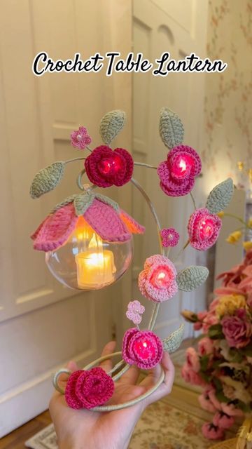 crochet table lantern in the shape of a flower with pink flowers and leaves