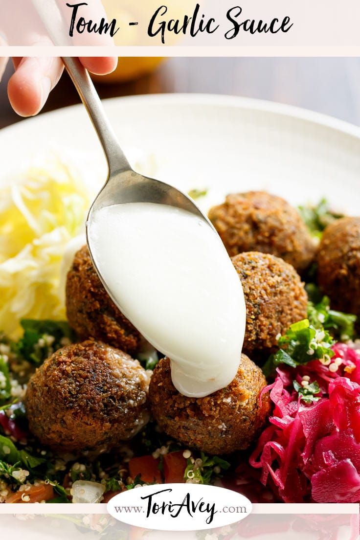 a white plate topped with meatballs covered in sour cream and garnished with veggies