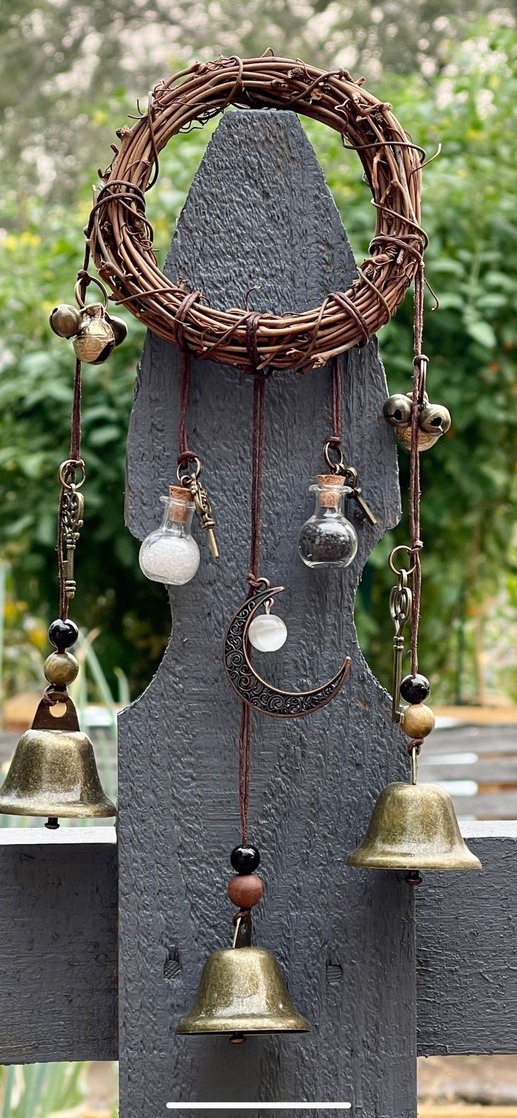 an assortment of bells hanging from a wooden fence