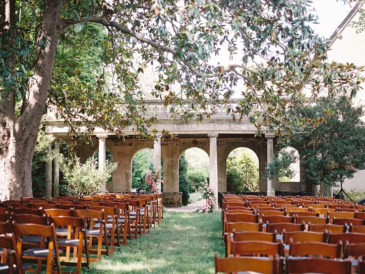 rows of wooden chairs sitting under a tree