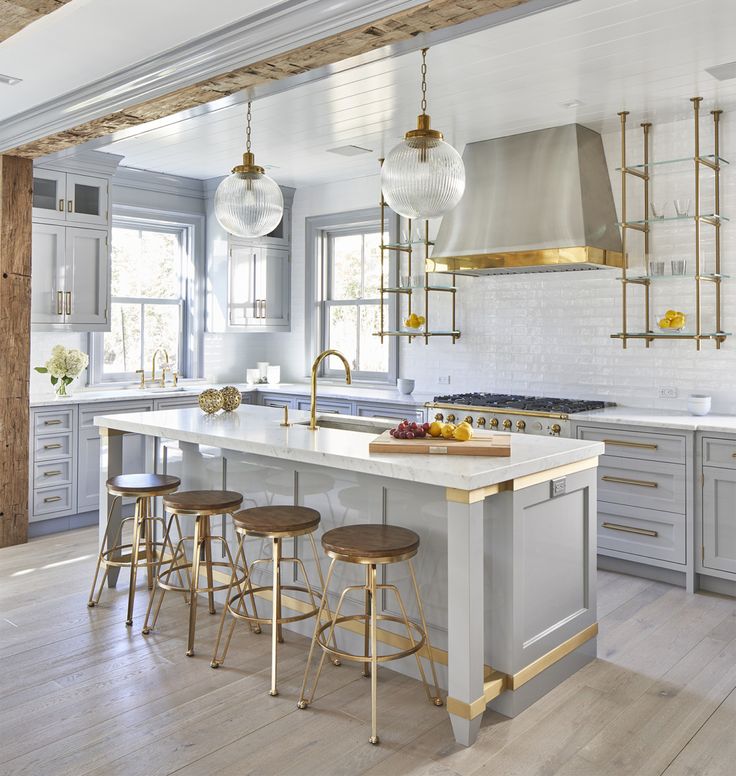 a kitchen with white cabinets and gold accents