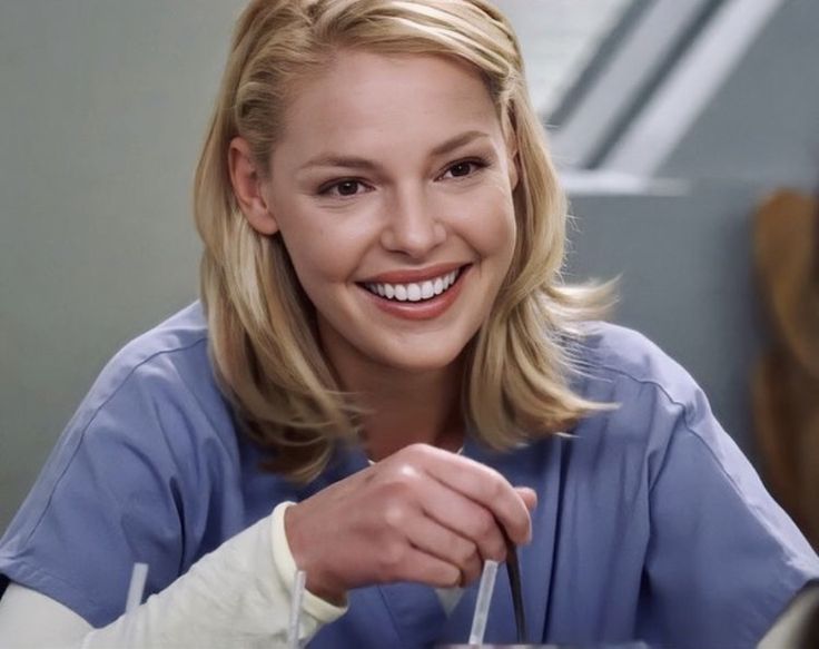 a woman in scrubs is smiling and holding a spoon