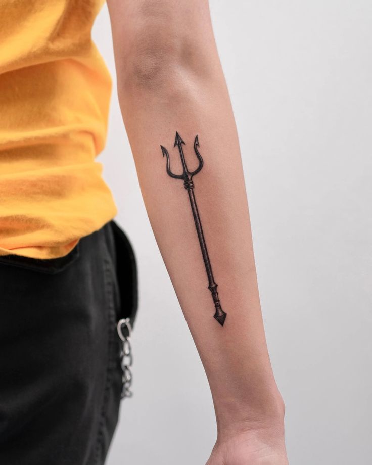 a person with a tattoo on their arm holding an arrow and pointing it at the viewer