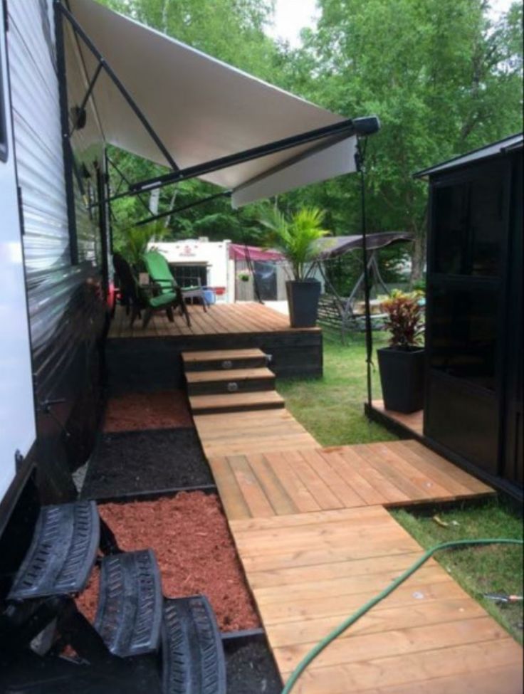 an rv is parked in the grass with its awning open and steps leading up to it