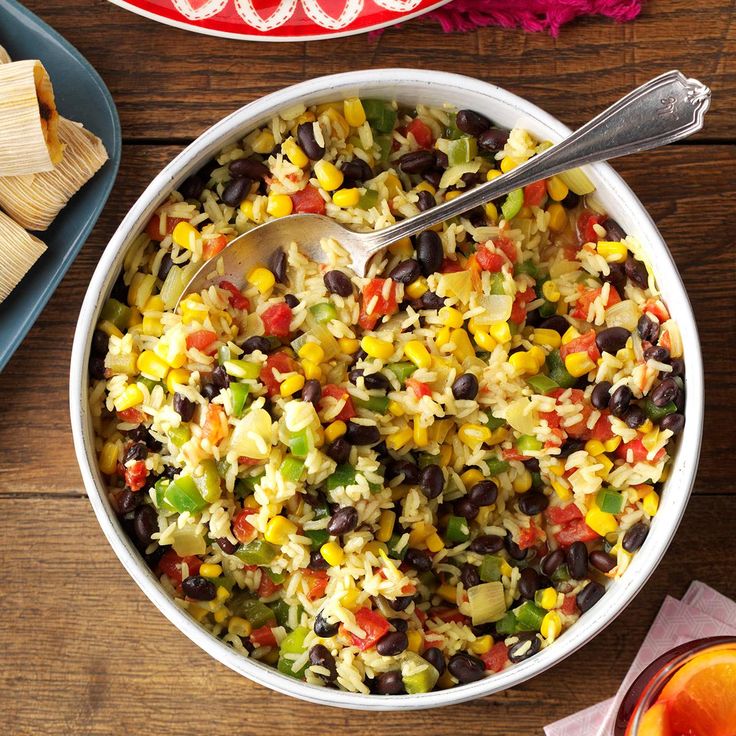 a plate filled with black beans, corn and cilantro on top of a table