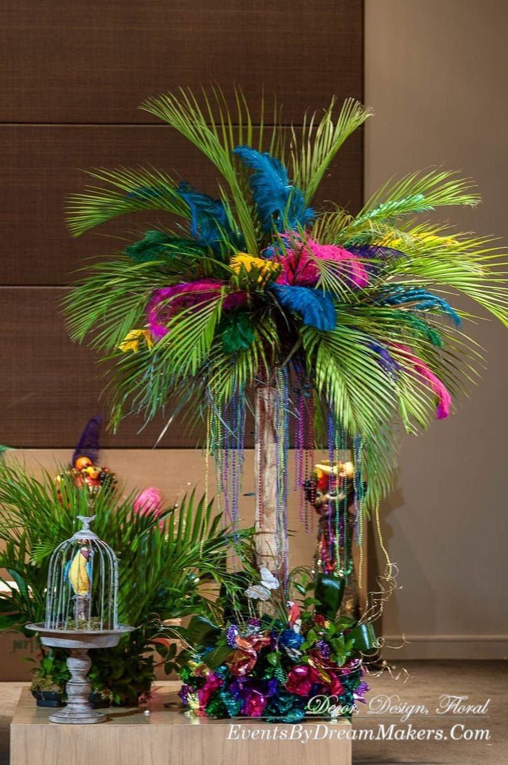 an arrangement of tropical plants and birdcages on a table