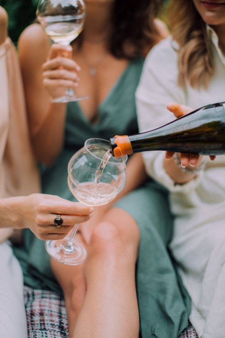 two women are holding wine glasses and pouring them