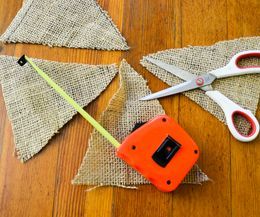 scissors, tape measure and burlap on the floor next to some pieces of cloth