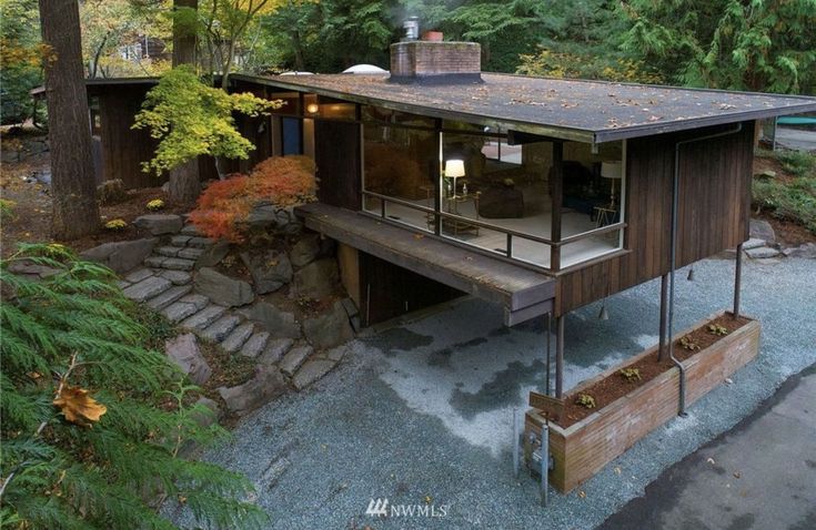 a small house in the middle of a wooded area with stairs leading up to it