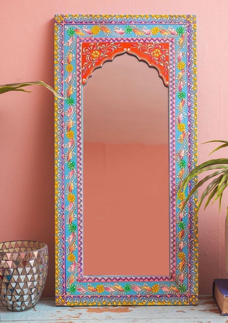 a mirror sitting on top of a table next to a potted plant and vase