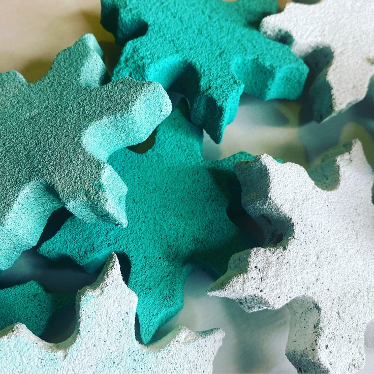 some blue and green colored sand sitting on top of each other in the shape of snowflakes