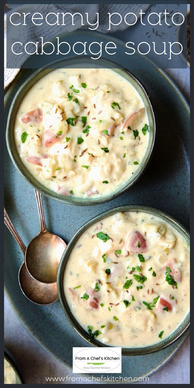 two bowls of creamy potato cabbage soup on a blue plate with spoons next to it