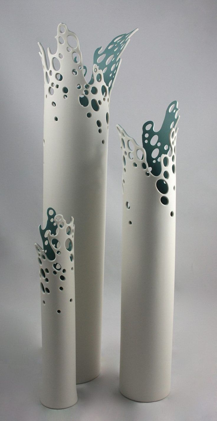 three tall white vases with holes in them