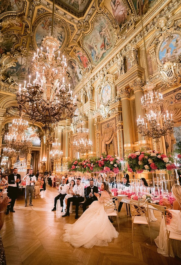 the bride and groom are sitting at their wedding reception in an ornately decorated ballroom