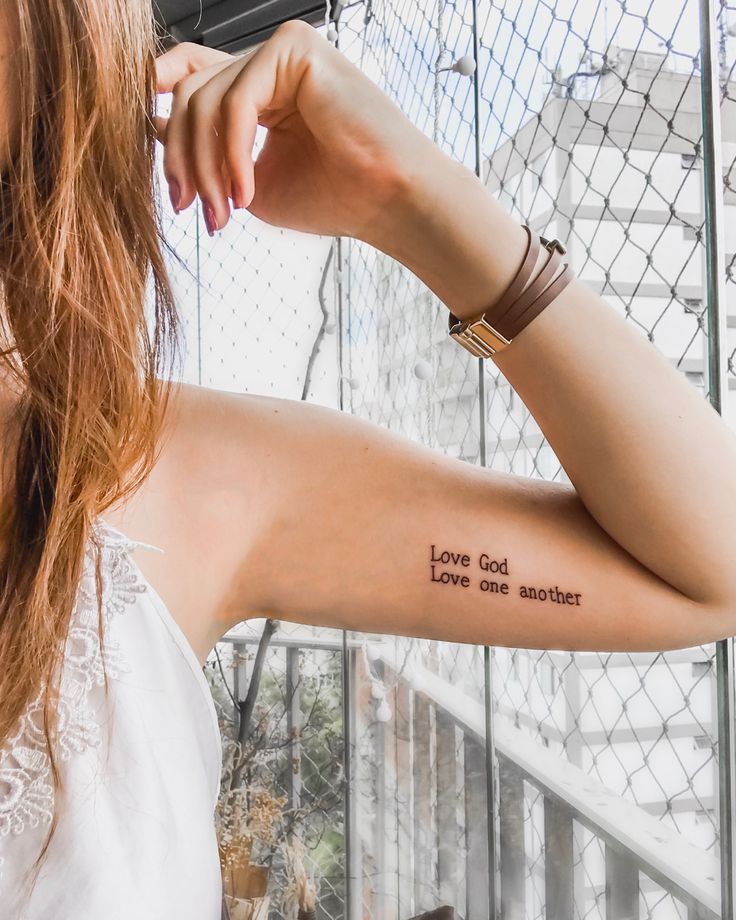 a woman with a tattoo on her arm that says love god, love one another