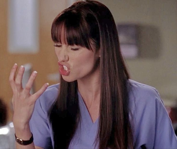 a woman in scrubs holding her hand up to her mouth