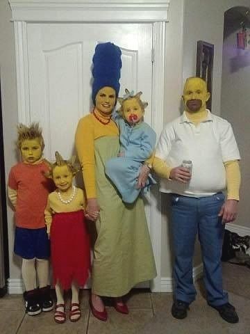 two adults and three children are dressed up as characters from the simpsons standing in front of a door