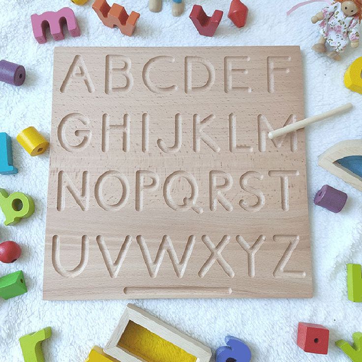 a wooden sign with letters and numbers on the floor next to toys that are scattered around it