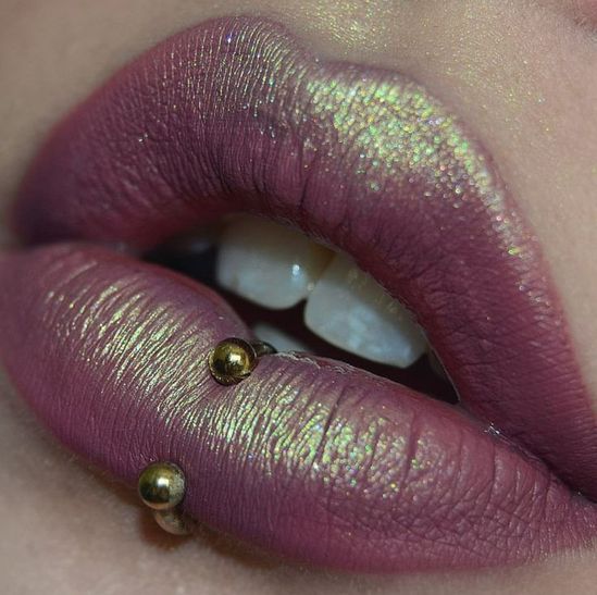 a close up shot of a woman's lips with purple lipstick and gold accents