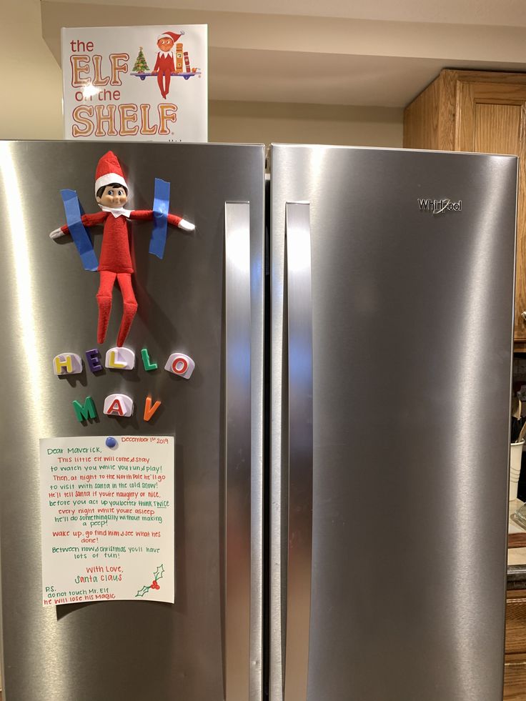 the elf is hanging on the side of the refrigerator with magnets attached to it