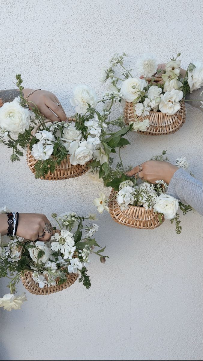 three people are holding flowers in baskets on the wall and touching them with their hands