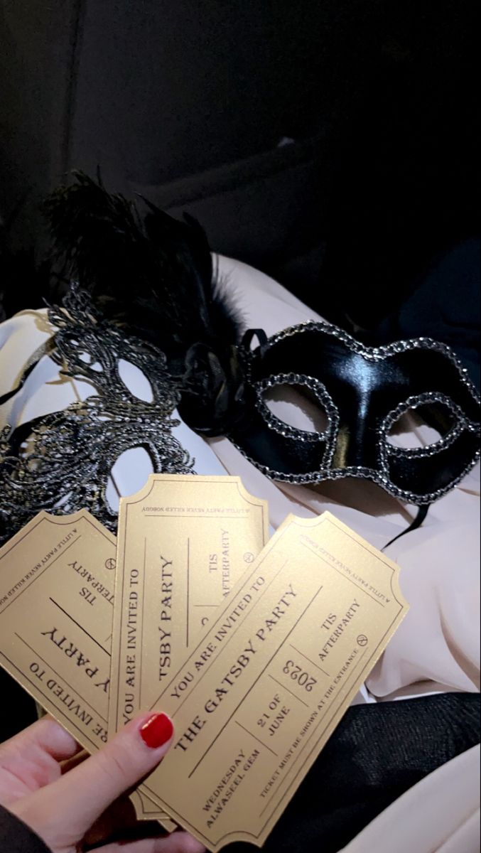 a person holding three tickets in front of a masquerade mask