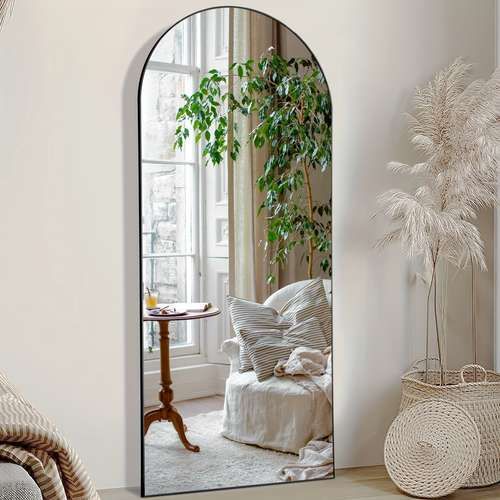 an arched mirror in a living room next to a couch and table with a potted plant