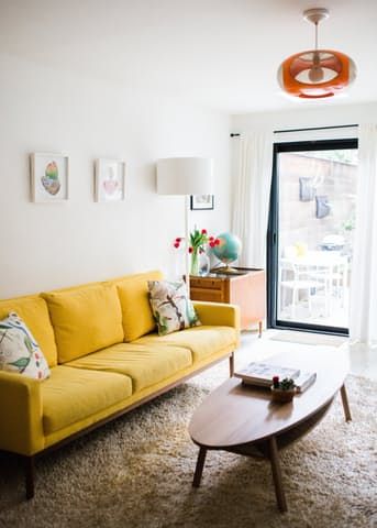 a living room with a yellow couch and coffee table