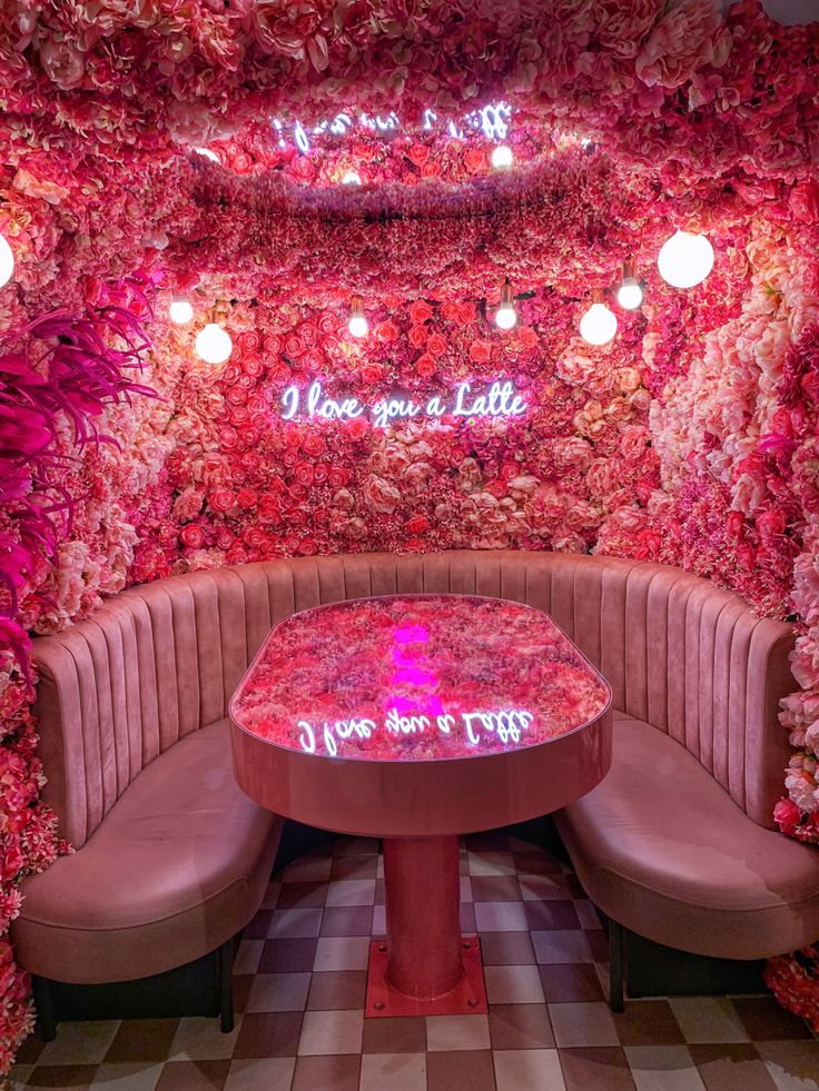 a booth with pink flowers on the walls and tables in front of it that says, you're a little late