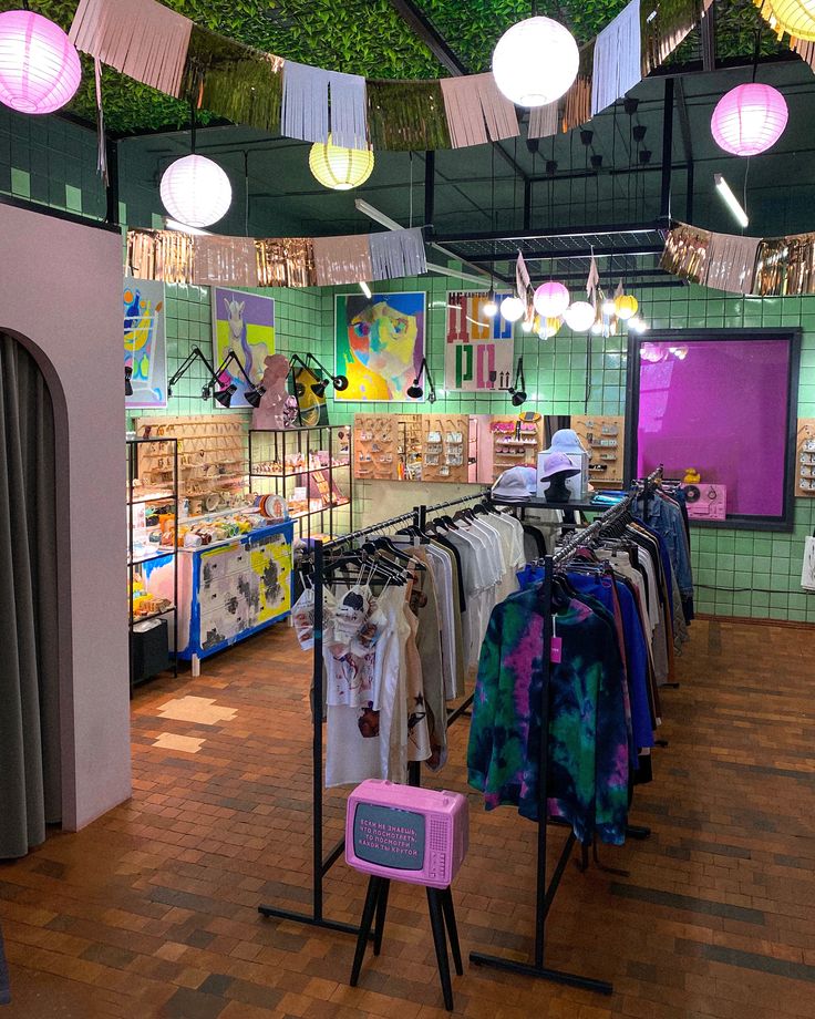 a clothing store with clothes on racks and lights hanging from the ceiling