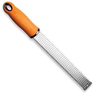 an orange and white knife with a black handle on a white background, showing the blade