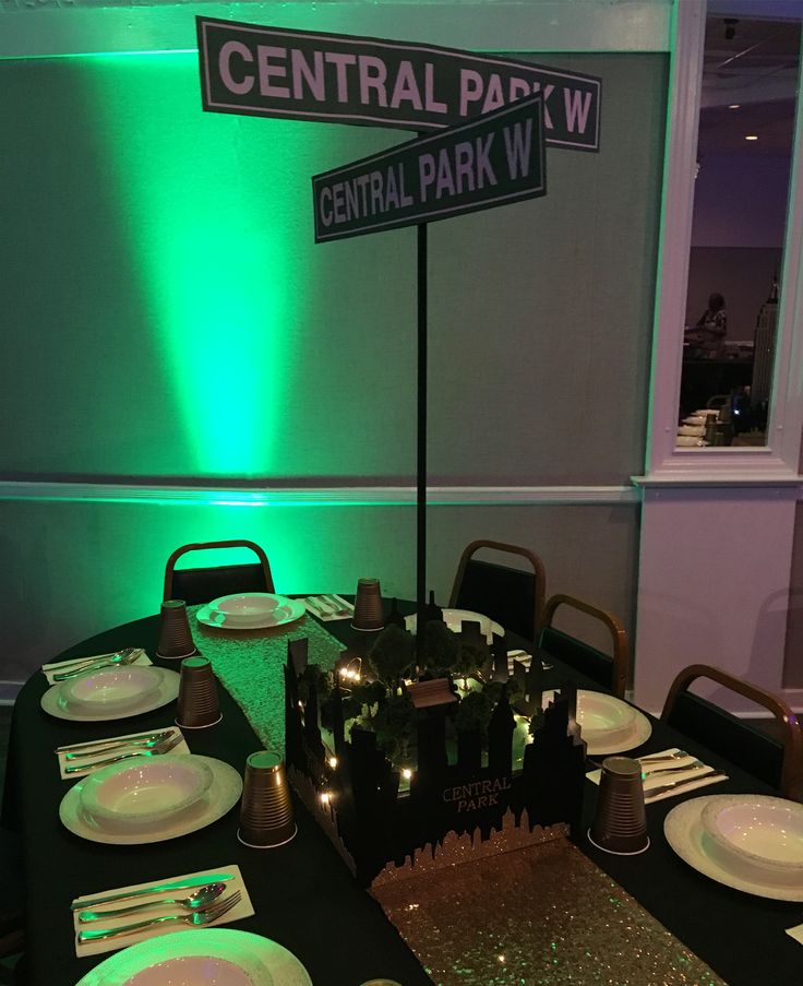 a table set up for a party with plates and silverware on it in front of a central park sign