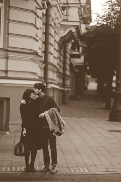 two people standing on the sidewalk hugging each other