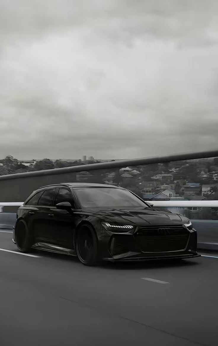 a black sports car driving down the road in front of some cars on a cloudy day