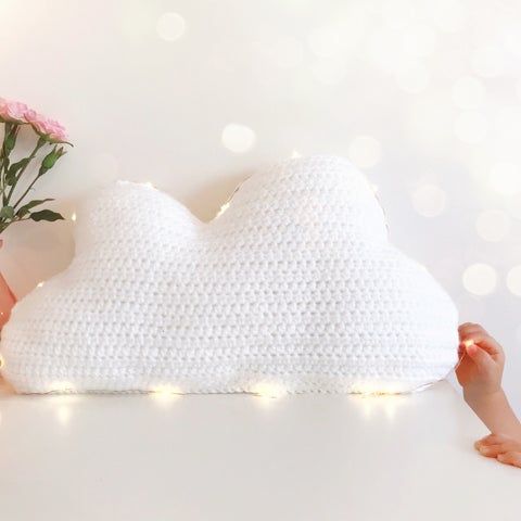 a person holding a pillow with lights on it and flowers in front of the pillow