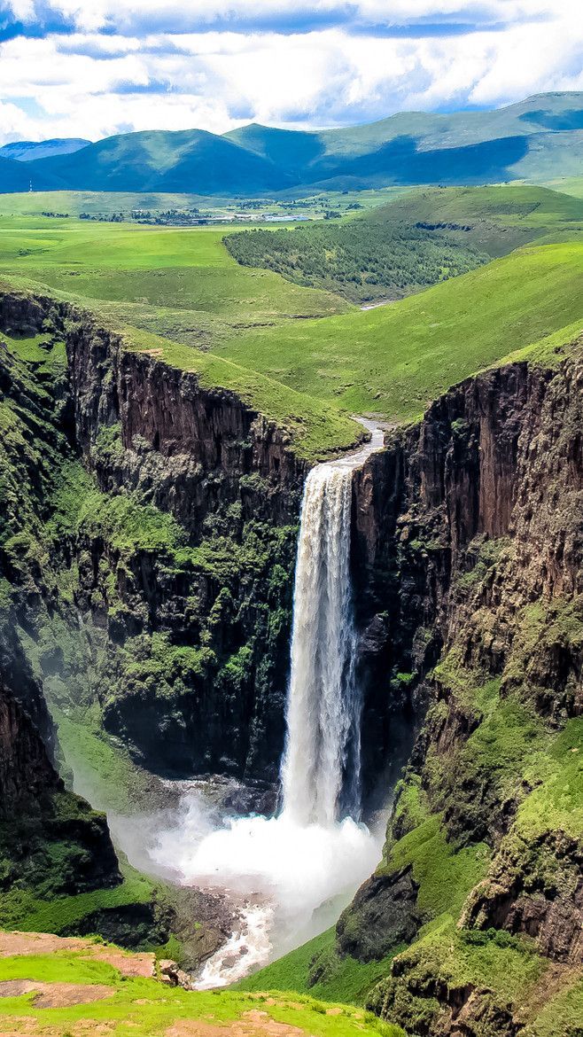 a large waterfall in the middle of a green valley