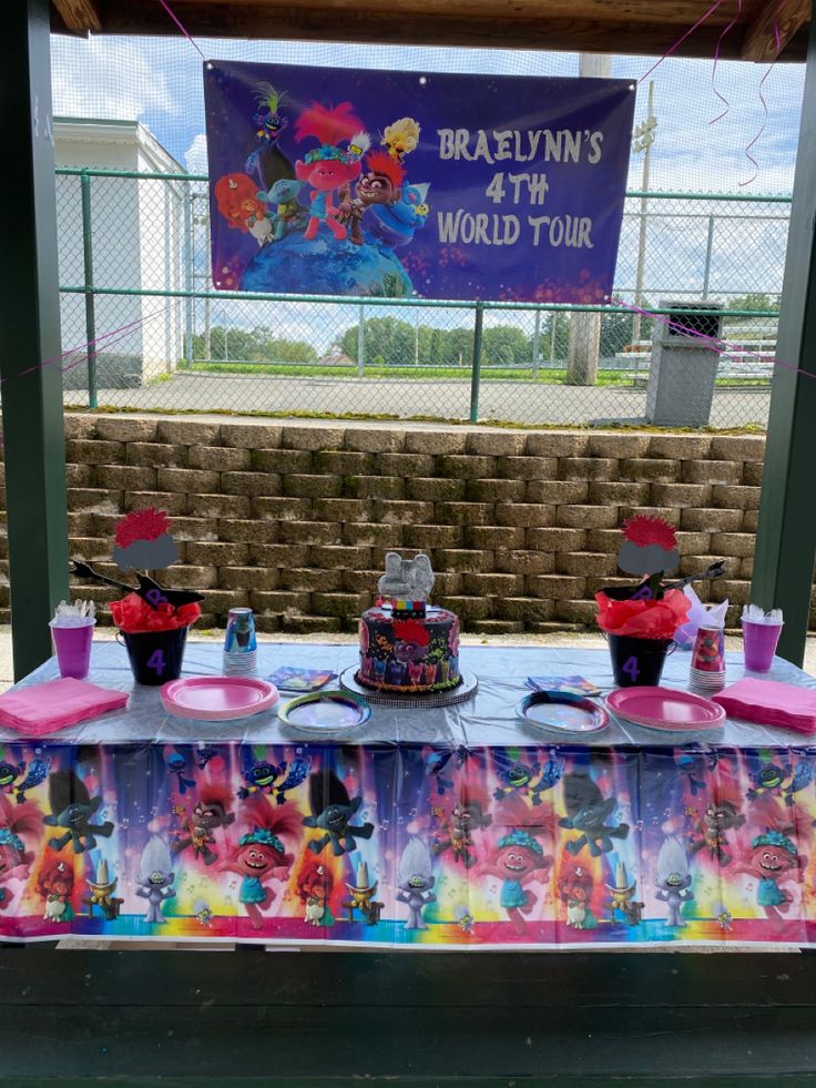 the table is set up for a birthday party with cake and cupcakes on it