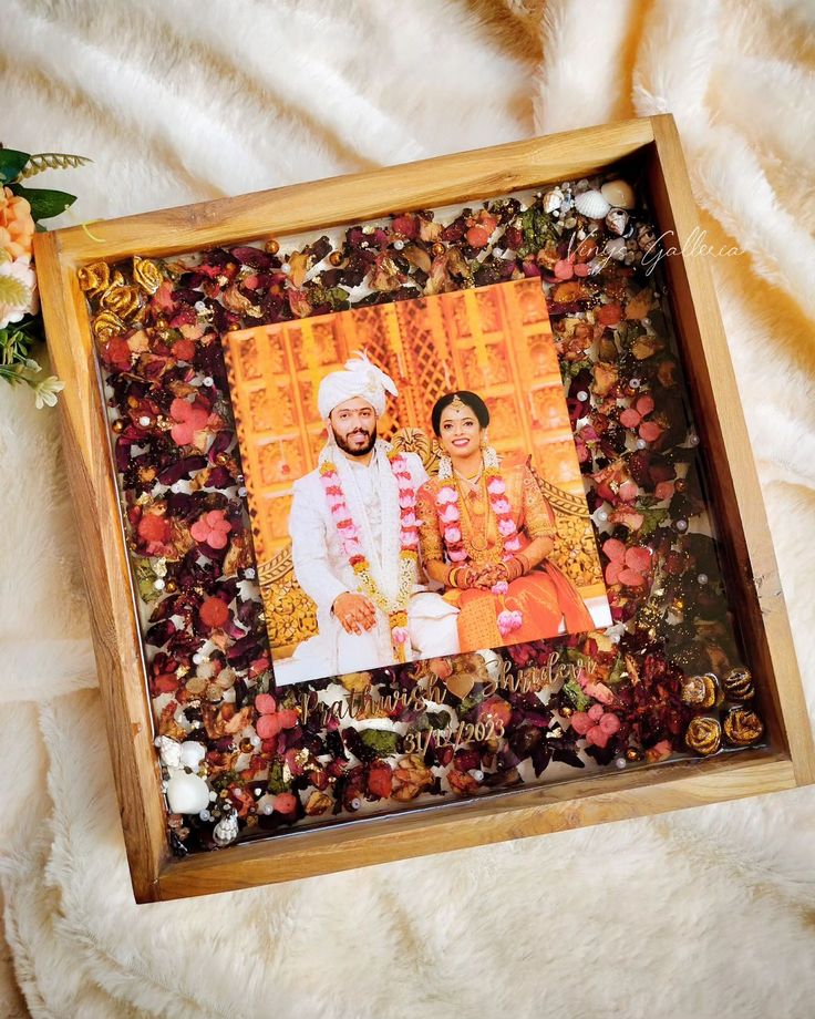 a wooden frame with an image of a bride and groom on it, surrounded by flowers