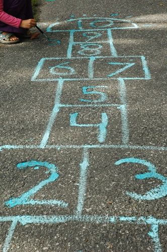 a child is playing with chalk on the ground and has an image of numbers painted on it