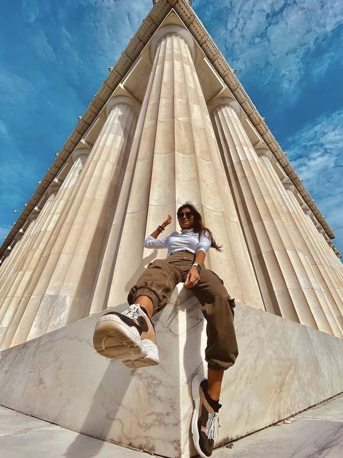 a man sitting on the side of a tall building with his feet up in the air