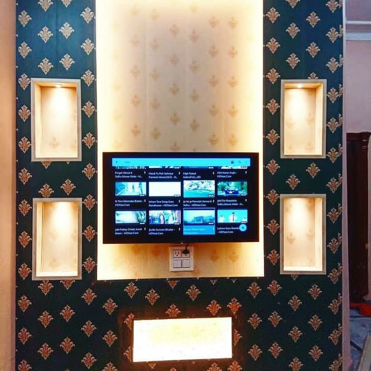 a television mounted to the side of a wall next to a mirror with lights on it