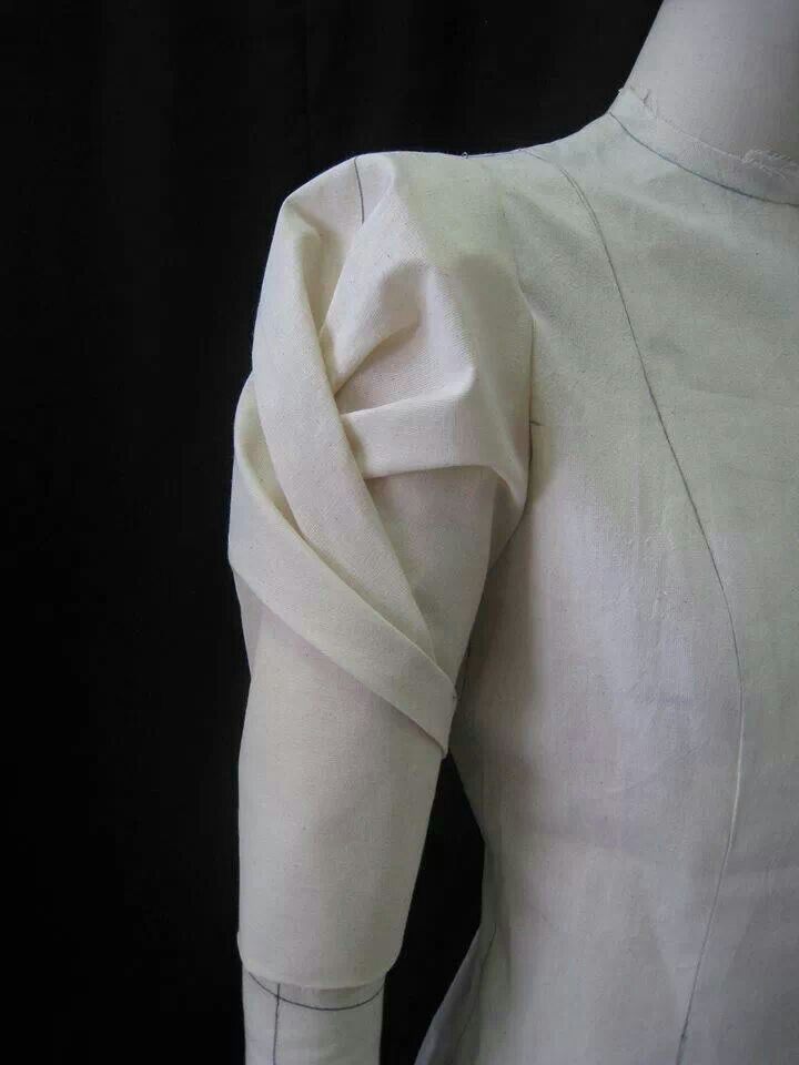 the back of a white dress with an asymmetrical neckline and sleeves