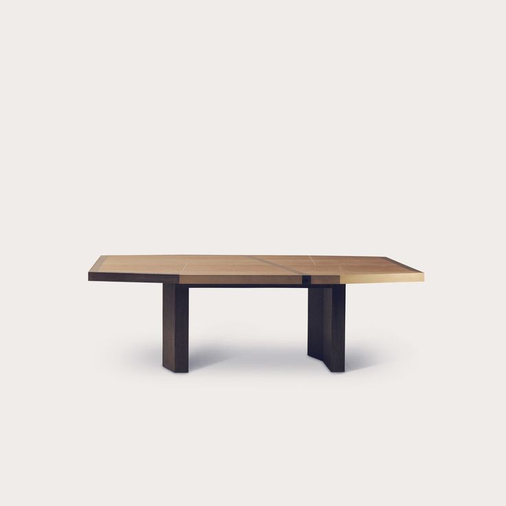 a wooden table sitting on top of a white floor next to a gray wall and black legs