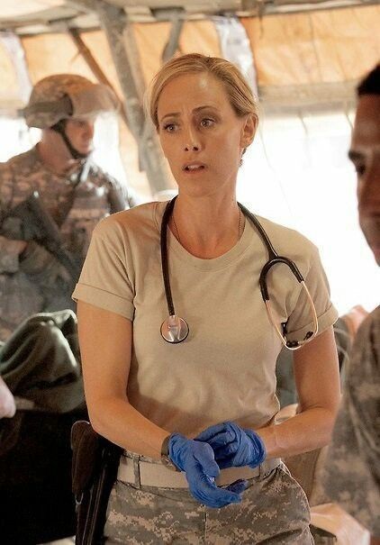 a woman in uniform standing next to other people and talking with each other while holding a medical stethoscope