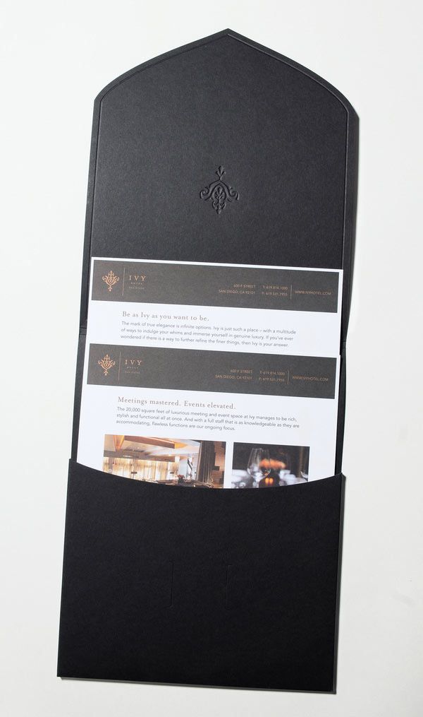 an open magazine holder on top of a white surface with black paper and pictures in it