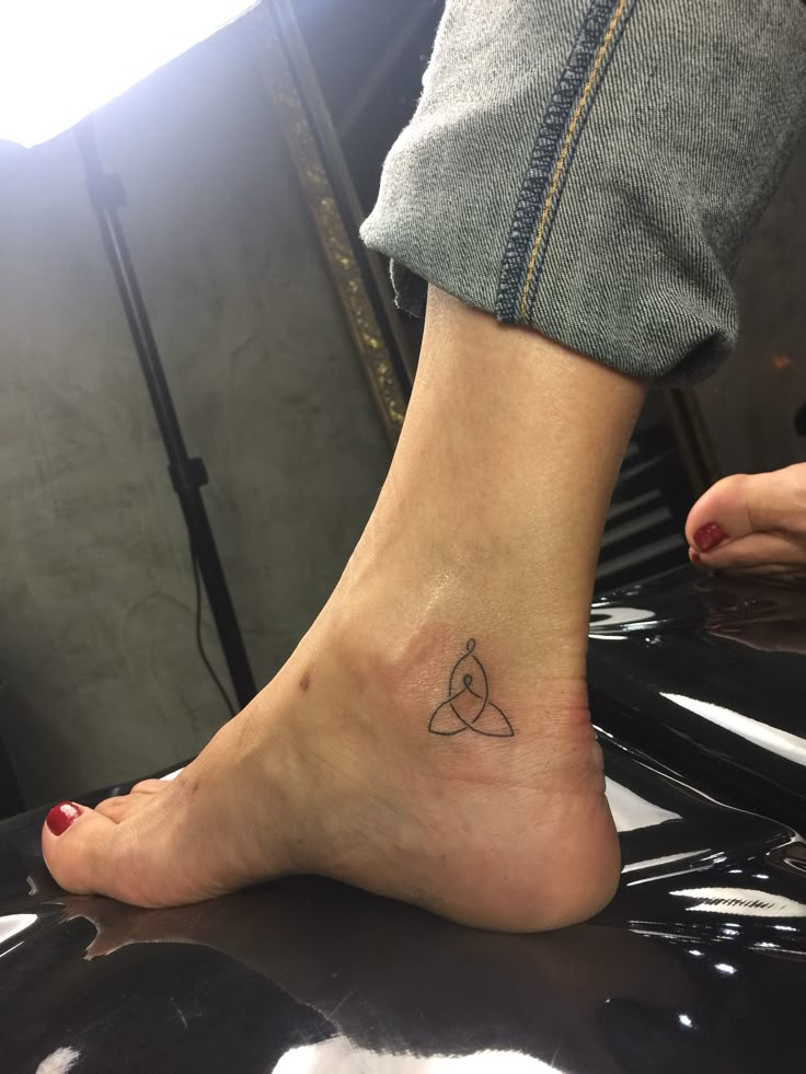 a woman's foot with a small triangle tattoo on it