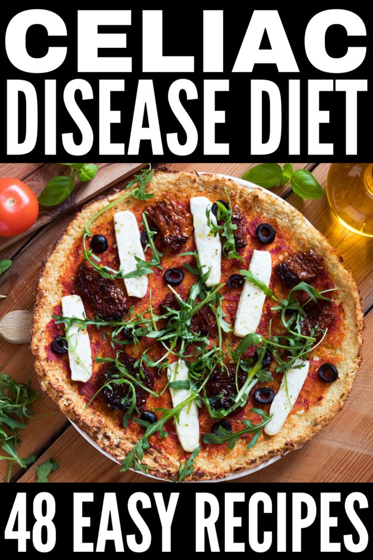 a pizza sitting on top of a wooden table next to a glass of beer and tomatoes