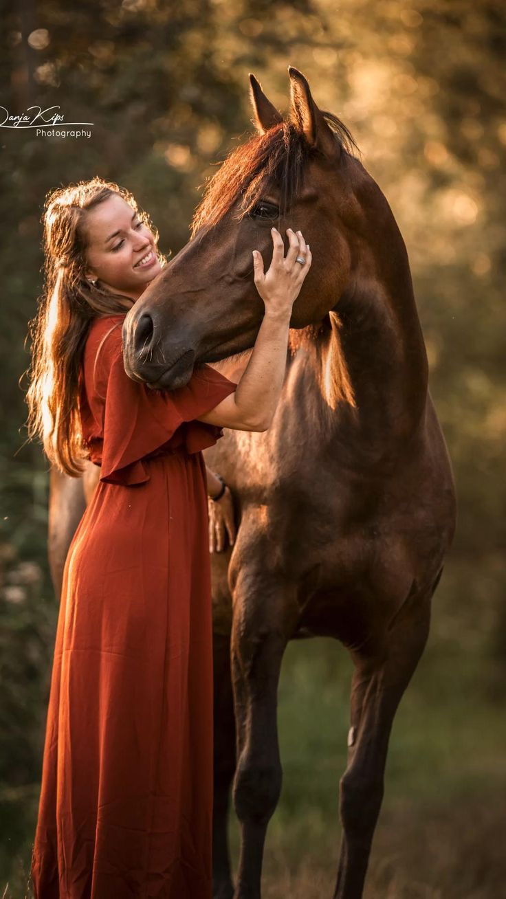 a woman in an orange dress petting a brown horse